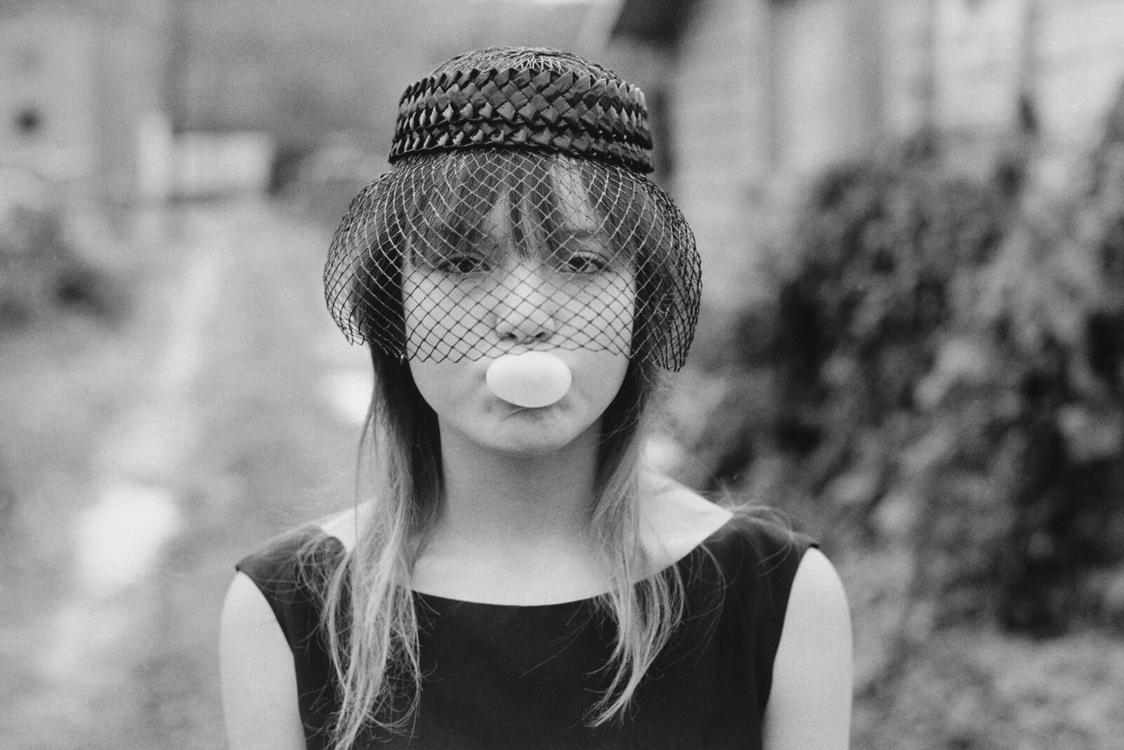 Photographie documentaire de Mary Ellen Mark : une jeune fille souriante, regard direct, environnement urbain, lumière naturelle
