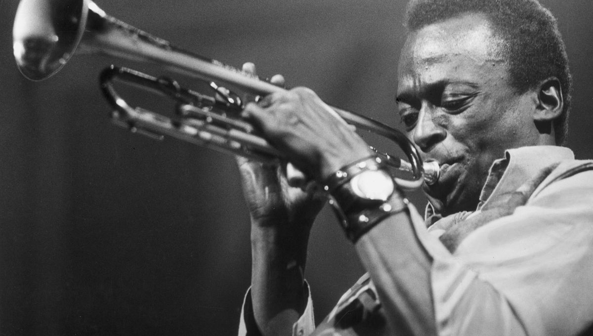 Les 5 Meilleurs Livres sur la Musique Jazz : Un Voyage à Travers l’Histoire et les Légendes du Jazz Miles Davis jouant de la trompette sur scène, lumière tamisée et ambiance club de jazz années 60