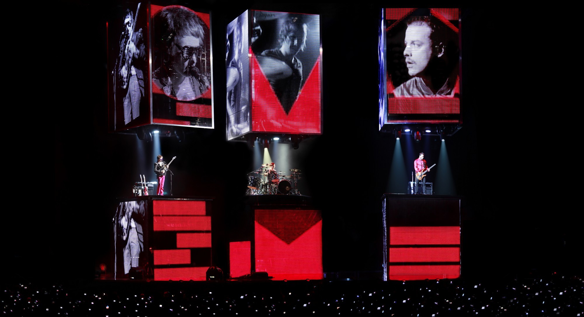 Muse : biographie, discographie et live Muse en concert, lumière bleue, Matt Bellamy guitare levée, foule en extase, festival plein air 2025