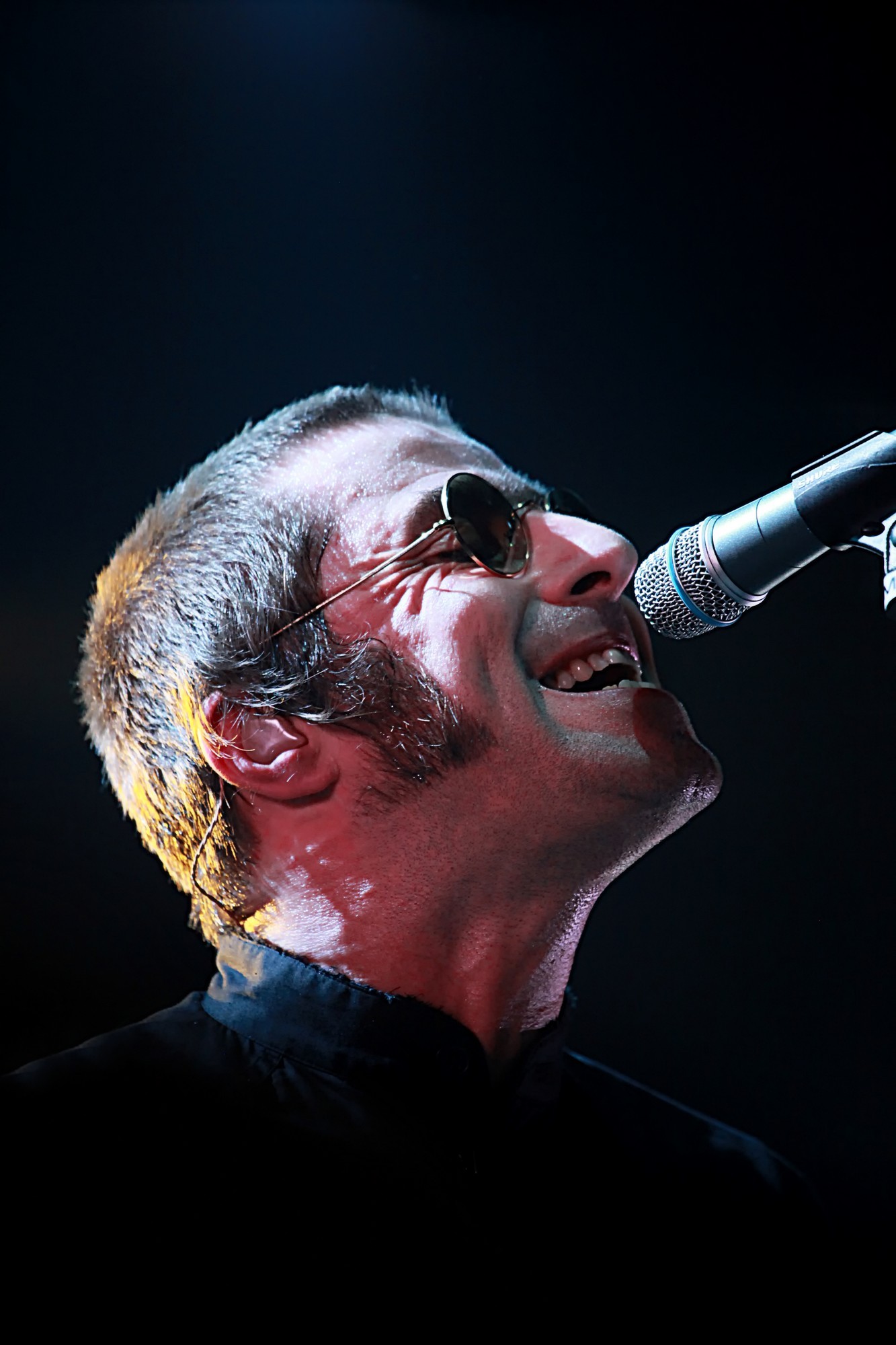 Liam Gallagher d'Oasis interprétant Wonderwall sur scène à Marseille, projecteurs et public en liesse