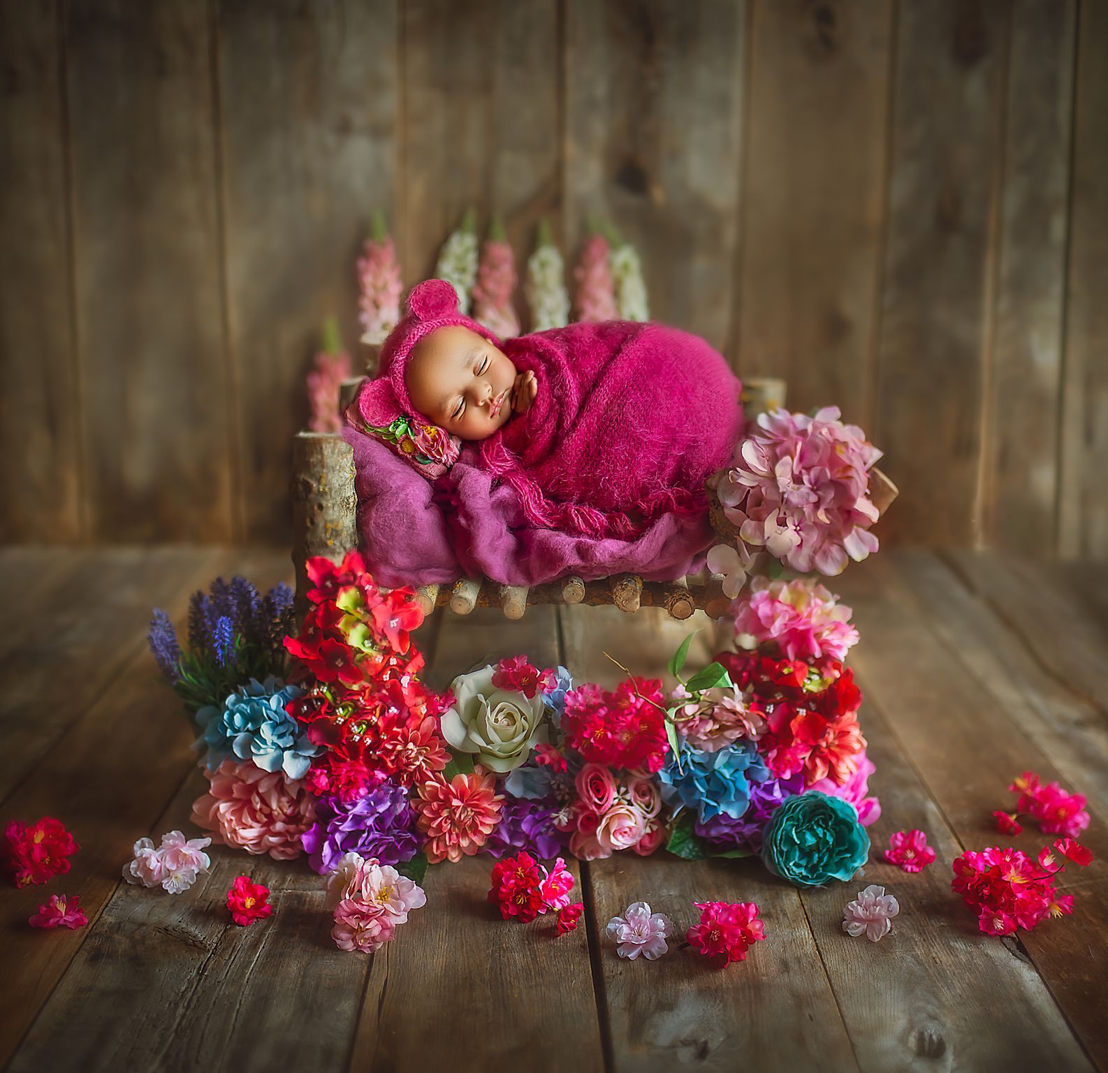 a baby sleeping on a small bed with flowers around it