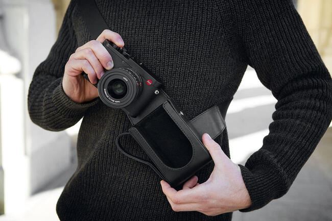 Leica Q2 : test et avis pour la photo de concert Leica Q2 en bandoulière d'un photographe dans la fosse d'un concert, foule et projecteurs en arrière-plan