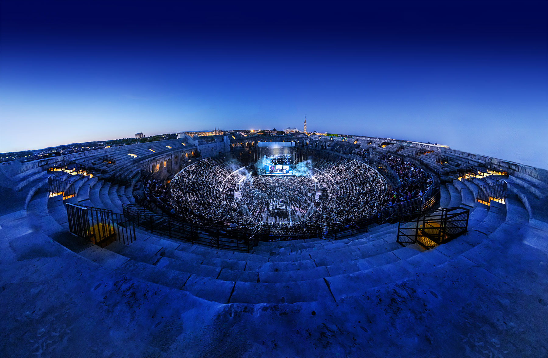 Les Arènes de Nîmes remplies un soir de concert du Festival de Nîmes, vues au crépuscule
