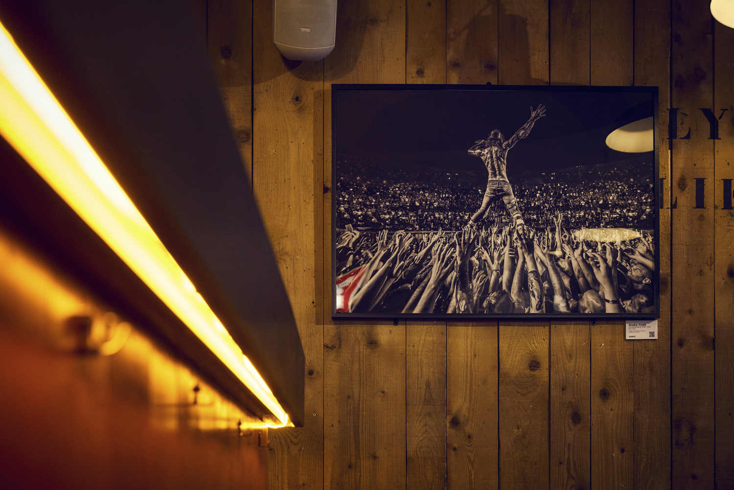 Tirage photo encadré d'un concert rock accroché sur un mur en bois de La Distillerie à Montpellier