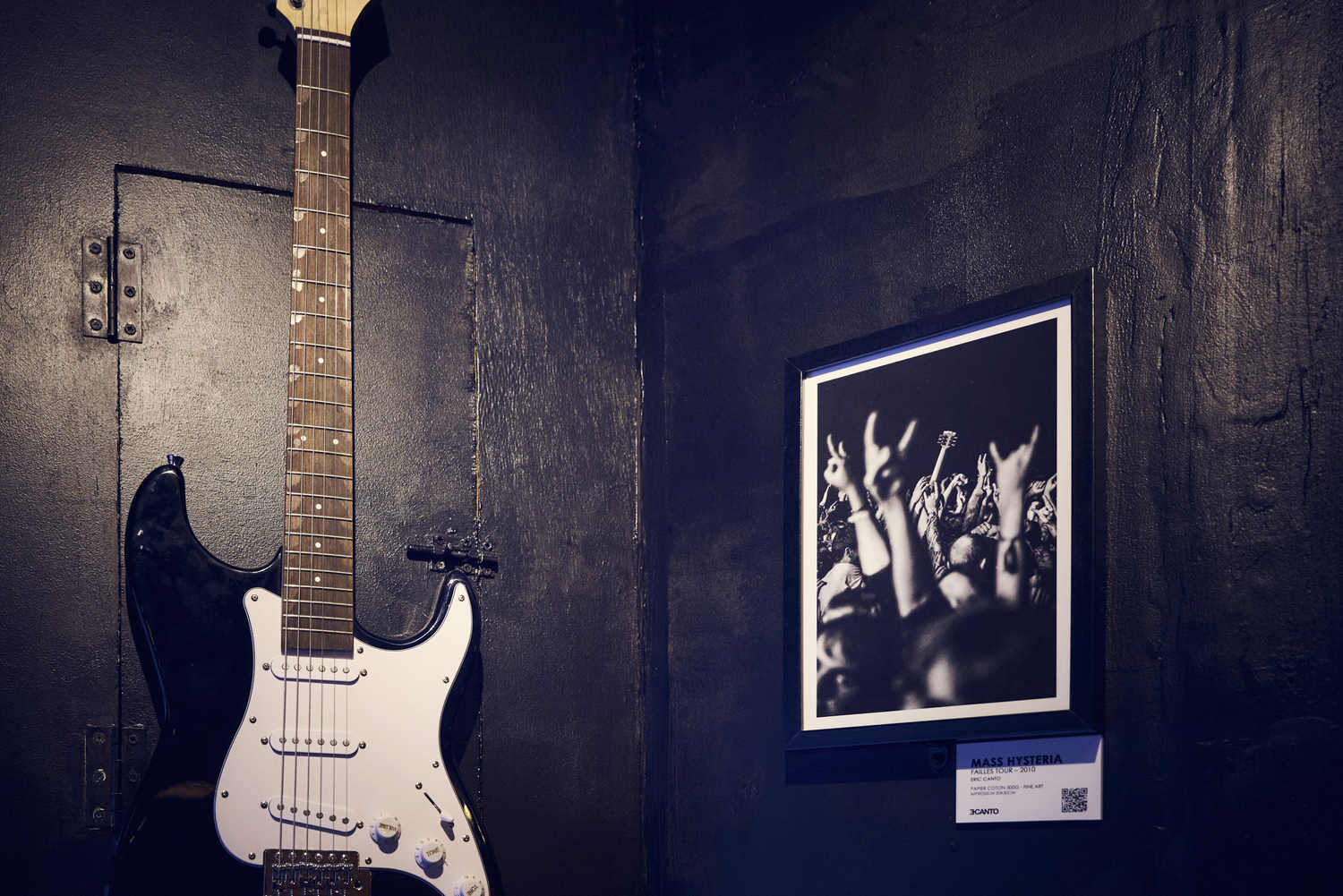 Guitare électrique et tirage photo de concert exposés côte à côte sur le mur de La Distillerie à Montpellier