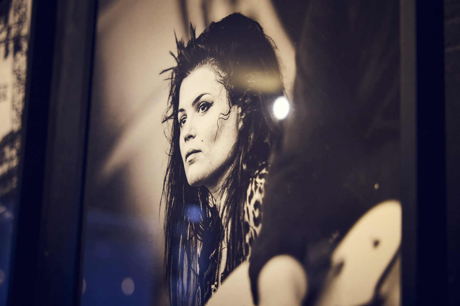 Tirage photo encadré d'un portrait d'artiste, exposé sur le mur noir de La Distillerie