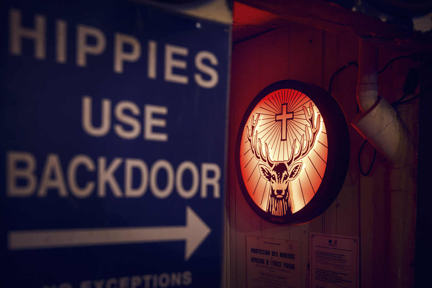 Décor du bar : pancarte Hippies use backdoor et enseigne lumineuse en forme de tête de cerf